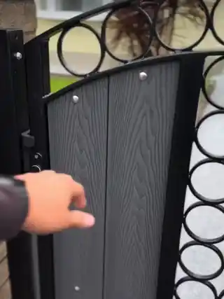 A garden gate swinging open onto a finished silver resin path lined with flowers